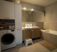 A bathroom in a 3-room apartment with a bathtub, cabinets, and a washing machine.