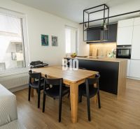 Dining room with a wooden table and a kitchen island in a 3-room apartment.