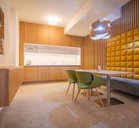 Kitchen in a holiday apartment with wooden cabinets, table, and green chairs.