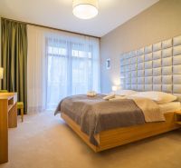 A bedroom in a holiday apartment with a large headboard and a wooden decor floor.