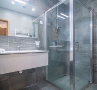 A bathroom in a vacation apartment with a spacious shower and a large mirror.