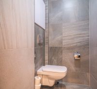 Bathroom with ceramic tiles and a wall-mounted toilet in a Holiday Apartment.