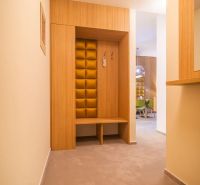 Interior of a holiday apartment with a coat rack wall and softly lit hallway.