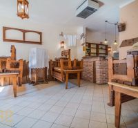 Gastro premises with wooden chairs and a brick bar, tiled floor.