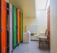 Colorful cabinets, wooden chairs, radiator, and slanted window in the dining area.