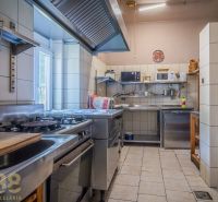 Professional kitchen with stainless steel equipment in catering spaces with ceramic tiles.