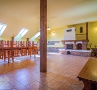 Gastro premises with a fireplace, floor with wooden decor, and chairs turned upside down.