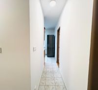 A hallway with tiles leading to the rooms in a 2-room apartment.