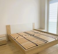 A bedroom with a wooden bed, nightstands, and a floor with a wood decor.