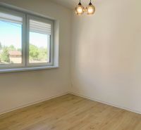 A room with a wooden decor floor in a 3-room apartment, light walls, window.