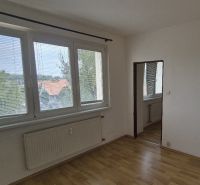 A room with white walls, large windows, and a floor with a wooden design.