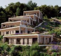 A villa in Dhërmi with a structured stone facade surrounded by lush greenery and flowers.