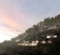 Villas in the town of Dhërmi located on a hillside surrounded by greenery at sunset.