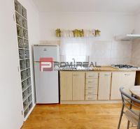 Compact kitchen in a studio apartment with wood-patterned flooring and a window above the sink.