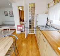 A kitchen in a studio apartment with wooden decor and natural daylight.