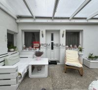 Terrace in front of a one-room apartment with garden furniture and decorative plants.