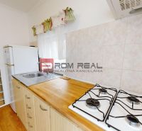 A kitchen in a studio apartment with a wooden decor floor and a glass wall.