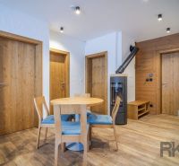 Recreational apartment with wood-patterned flooring, a round table, and a wood-burning stove.