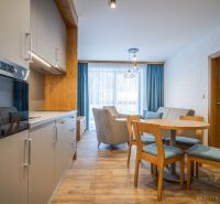A kitchen in a holiday apartment with a wood-decor floor and a dining table.