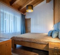 Bedroom in a holiday apartment with a wooden ceiling, bed, and floor with a wooden decor.