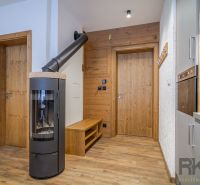 Interior of a holiday apartment with a fireplace, kitchen, and wood-decorated flooring.