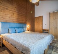 Bedroom with wood-patterned flooring in a holiday apartment. Elegant bed with upholstered headboard.