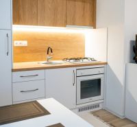 A kitchenette in a studio apartment with a wooden decor floor and comfortable lighting.