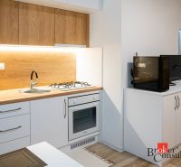 A kitchenette in a studio apartment with a wood decor and appliances.