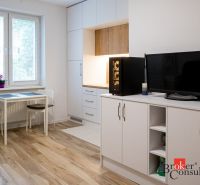 Studio apartment with a kitchenette, dining table, and wooden decor flooring.