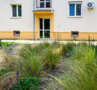 Apartment building with a grassy yard and flowers on Herlianska Street in Bratislava-Ružinov.