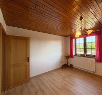 A room with a wooden decor floor and wooden paneling in a family house.