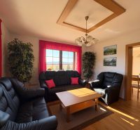 Living room with black seating, wooden table, and red curtains in a family house.