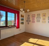 A room in a family house with a floor featuring a wooden decor, embroidered pictures on the wall.