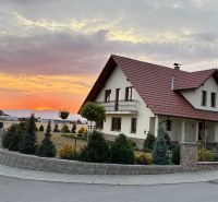 A family house in Trenčianska Turná at sunset, surrounded by a landscaped garden.