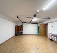 A garage with opening doors and brown tiles in a family house.
