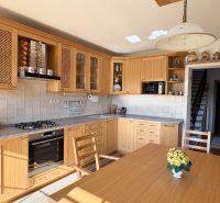 A kitchen in a family house with wooden cabinets and light walls.