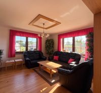 Living room in a family house with a black sofa and a wooden decor floor.