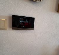 Thermostat and switch on a white wall in a family house.