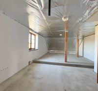 Attic space with an unfinished floor, metal ceiling, and wooden columns in a family house.