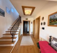 Interior of a family house with wooden decor, staircase, and artistic decorations on the wall.
