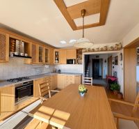 A kitchen in a family house with a wooden decor floor, light furniture, and decorations.