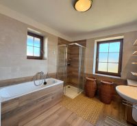 Spacious bathroom in a family house with a wooden decor floor and a bathtub.