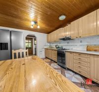 A kitchen in a family house with a light wooden decor on the ceiling and kitchen cabinets.