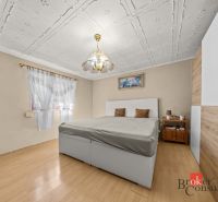 Bedroom in a family house with a wooden decor floor and an elegant chandelier.