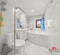 A bathroom with marble tiles and a blue curtain in a family house.