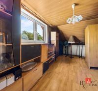 Attic room in a family house with wooden furniture and a view of the garden.
