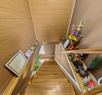 A staircase in a family house with a wooden decor floor, decoration, and flowers on the shelves.