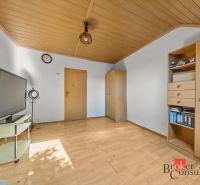 A room in a family house with a wooden decor floor, a television, and furniture.