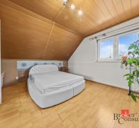 Bedroom in a family house with a bed, decorative wall, and floor with wood decor.