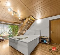 Bedroom in a family house with a bed, a plant, and stairs, floor with wood decor.